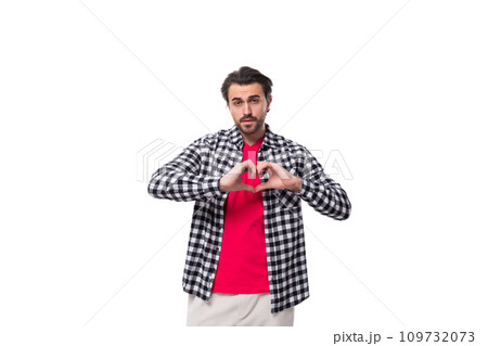 a young european man with black hair and an unshaven beard in a shirt shows a heart a young european man with black hair and an unshaven beard in a shirt shows a heart 109732073