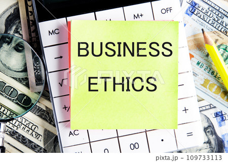 BUSINESS ETHICS text, a word written on a sticker lying on a calculator against a background of money 109733113