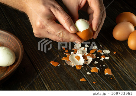 Cooking a delicious lunch with boiled eggs on the kitchen table. Shelling an egg with the hands of a chef Cooking a delicious lunch with boiled eggs on the kitchen table. Shelling an egg with the hands of a chef 109733963