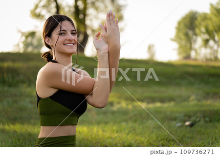 The concept of master classes and seeds. Girl smiling at the camera performing yoga exercises on the background of summer nature The concept of master classes and seeds. Girl smiling at the camera performing yoga exercises on the background of summer nature 109736271