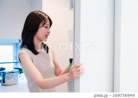 冷蔵庫を開けて物を取り出す若い女性 冷蔵庫を開けて物を取り出す若い女性 109736949