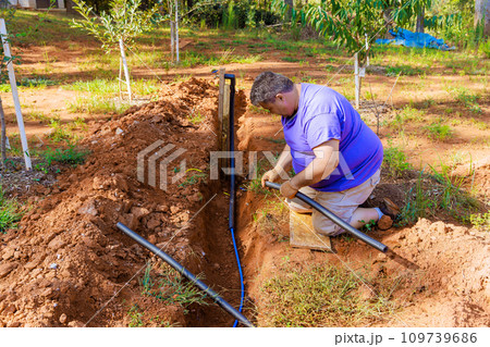 Underground PVC water pipe is thermally insulated with PE foam coated by plumber 109739686