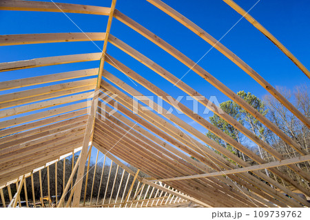 Construction of wooden frame truss roof for new house with support wooden beams 109739762