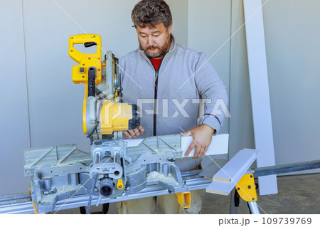 Cutting base moldings with chop saw is task performed by trim worker 109739769