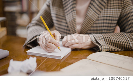 Close-up of senior woman taking notes and crumpling paper, brainstorming 109740517