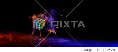 Glass of martini cocktail standing against dark background with neon light with smoke. Splashes 109740579