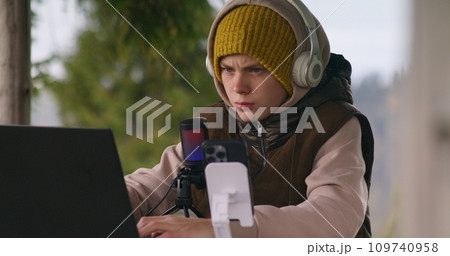 Teenager sits in wooden gazebo and surfs internet during holidays Teenager sits in wooden gazebo and surfs internet during holidays 109740958