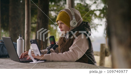 Young streamer uses laptop and phone on tripod for streaming 109740977