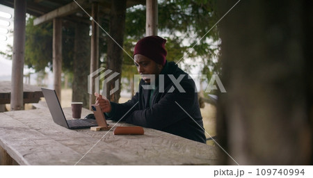 Man sits in wooden gazebo and talks at video call using phone 109740994