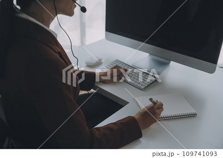Beautiful female call center operator working on computer in office Beautiful female call center operator working on computer in office 109741093