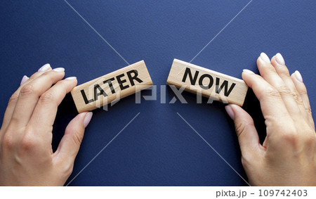 Now vs Later symbol. Concept word Now vs Later on wooden blocks. Businessman hand. Beautiful deep blue background. Business and Now vs Later concept. Copy space Now vs Later symbol. Concept word Now vs Later on wooden blocks. Businessman hand. Beautiful deep blue background. Business and Now vs Later concept. Copy space 109742403