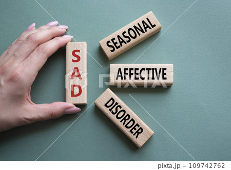 Sad - Seasonal Affective Disorder symbol. Wooden blocks with words Sad. Businessman hand. Beautiful grey green background. Business and Sad concept. Copy space. Sad - Seasonal Affective Disorder symbol. Wooden blocks with words Sad. Businessman hand. Beautiful grey green background. Business and Sad concept. Copy space. 109742762