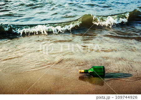 Message bottle on beach in waves 109744926