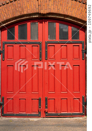 A red wooden portal for several cars. Old Fire station. arch and window with metal decorations. 109749692