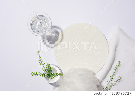 A round white podium is displayed with props on a white background. Ideal space for product display. Advertisements for shower gel, shampoo and other toiletries. 109750727
