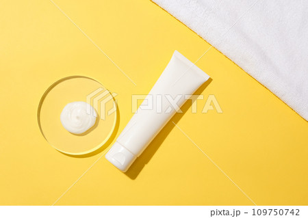 A drop of white cosmetics on a glass podium and an unlabeled cosmetic tube displayed on a yellow background. Build a cosmetic brand with mockups. A drop of white cosmetics on a glass podium and an unlabeled cosmetic tube displayed on a yellow background. Build a cosmetic brand with mockups. 109750742