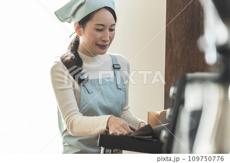 オーブンからケーキを取り出すエプロン姿の女性 オーブンからケーキを取り出すエプロン姿の女性 109750776