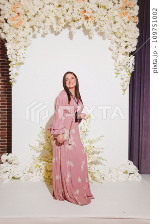 woman in a pink dress with a badge on the zone for taking photos at the party.  109751002