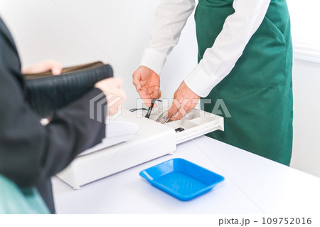 レジスターで現金支払い・会計・精算・するコンビニ・スーパーマーケットの店員 109752016