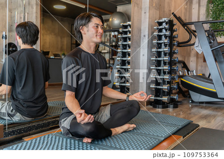 スポーツジムでヨガ・ピラティス・瞑想・マインドフルネスする若いアジア人男性 109753364