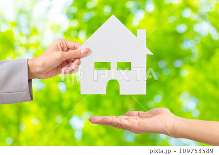家の形をした白い紙を渡す女性の手元 家の形をした白い紙を渡す女性の手元 109753589