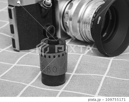 classic 135 film cassette with retro camera background classic 135 film cassette with retro camera background 109755171