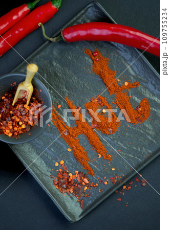 Chili pepper isolated on a black background. Knitted hot chili pepper tied with a rope. Red chili pepper cut into pieces on a black background. 109755234