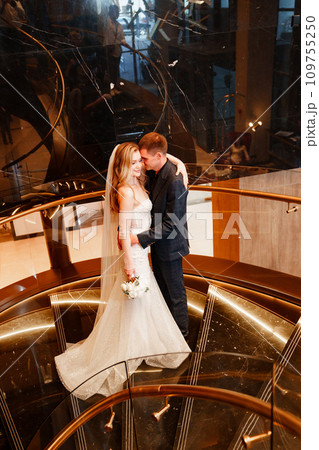 Bride and groom embracing on a golden spiral staircase.  109755250