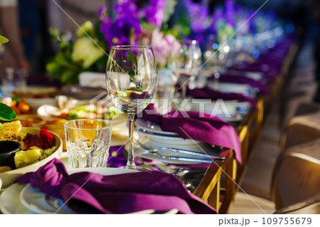 Beautiful festive table setting with flowers and purple napkins. Beautiful festive table setting with flowers and purple napkins. 109755679
