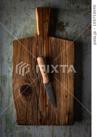 Big kitchen knife lying on an old cutting board 109758040