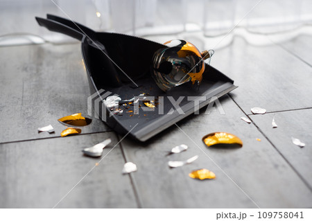 Broken Golden Christmas ball on scoop on the floor Broken Golden Christmas ball on scoop on the floor 109758041