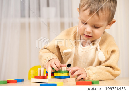 A two-year-old boy plays with wooden toys to develop logic and motor skills 109758478