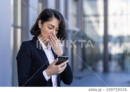 Businesswoman received notification message with bad news, woman reading online on phone, upset and confused sad using smartphone app, outside office building, walking in business suit. Businesswoman received notification message with bad news, woman reading online on phone, upset and confused sad using smartphone app, outside office building, walking in business suit. 109759328