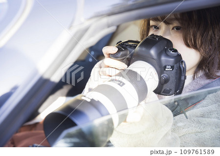 車内でカメラを持って張り込む若い女性記者 109761589