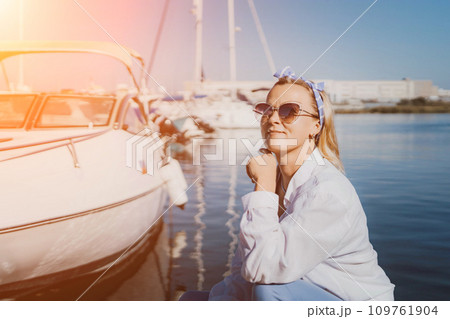 Woman in white shirt in marina , surrounded by several other boats. The marina is filled with boats of various sizes, creating a lively and picturesque atmosphere. Woman in white shirt in marina , surrounded by several other boats. The marina is filled with boats of various sizes, creating a lively and picturesque atmosphere. 109761904