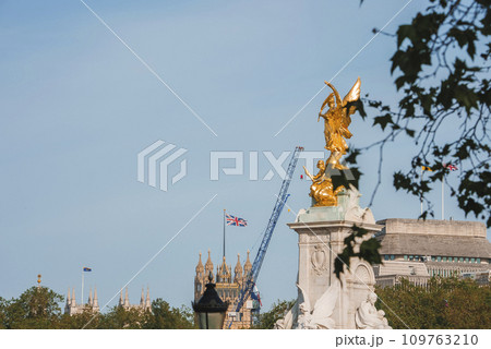 The Golden Angel of Victoria Memorial. Buckingham Palace by famous statue of London. Big Ben Parliament with clear sky in background. The Golden Angel of Victoria Memorial. Buckingham Palace by famous statue of London. Big Ben Parliament with clear sky in background. 109763210