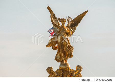 The Golden Angel of Victoria Memorial. Iconic Symbol of London on sunny day. Famous sculpture with blue sky in background. The Golden Angel of Victoria Memorial. Iconic Symbol of London on sunny day. Famous sculpture with blue sky in background. 109763280