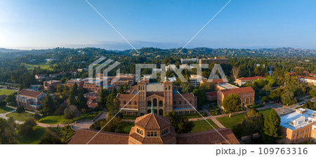 Aerial view of UCLA's campus in Westwood, Los Angeles, highlighting a blend of Romanesque and modern architecture amid verdant lawns and red-brick buildings on a sunny day. 109763316