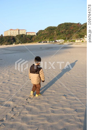 冬の砂浜を散歩する子ども 109764378