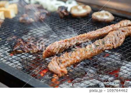 バーベキューで焼いている炭火焼のグリル 109764462