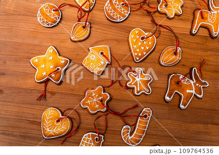 Wooden background with lots of gingerbread Christmas gingerbread in the shape of a house, heart. Deer. star, christmas tree toy, ball with white glaze. High quality photo 109764536