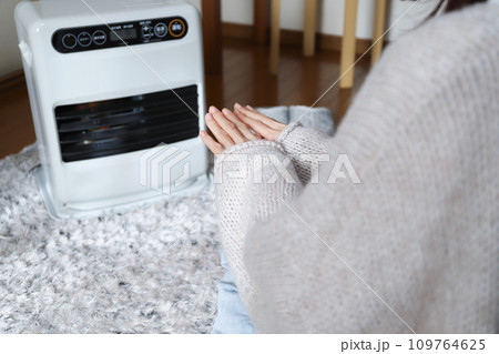 ファンヒーターで暖まる女性 109764625