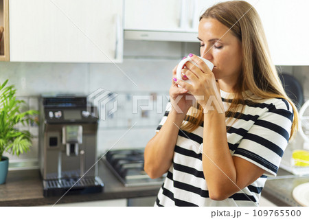 Attractive woman enjoying freshly made coffee in the kitchen in the morning 109765500