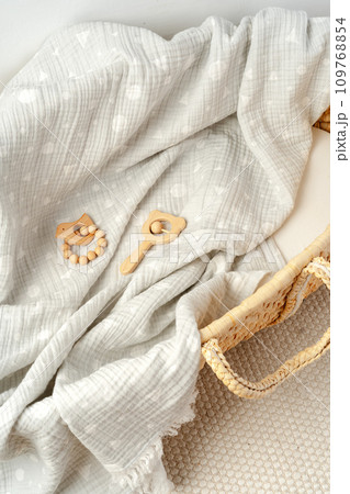 Muslin blanket and wooden toys in baby cradle 109768854