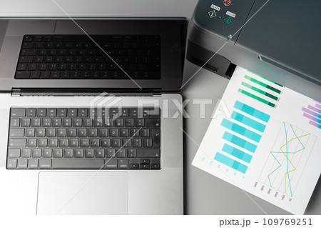 Modern printer with paper and laptop on table in office 109769251