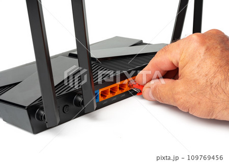 Man's hand plugging internet cable into wifi router 109769456