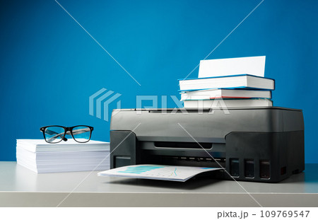 Laser printer on desk against blue background. 109769547