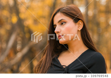 Close up portrait of pretty indian young woman enjoying warm autumn sunny day vacation outdoors copy space. Generation z and gen z concept. Fall Season 109769548