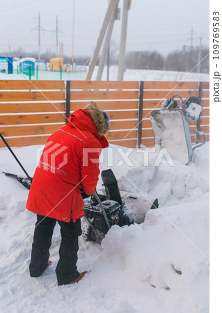 A man clear snow from backyard with snow blower. Winter season and snow blower equipment A man clear snow from backyard with snow blower. Winter season and snow blower equipment 109769583