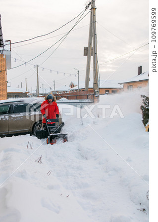 A man clear snow from backyard with snow blower. Winter season and snow blower equipment A man clear snow from backyard with snow blower. Winter season and snow blower equipment 109769599